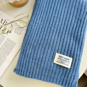 Blauer gerippter Strickschal Detailansicht mit Vintage-Etikett und stilvollem Zubehör.