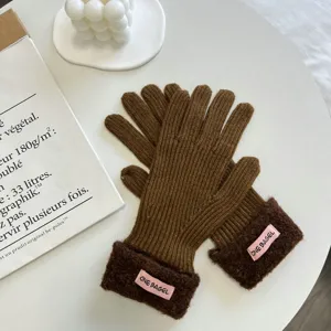Detailansicht brauner Winter-Strickhandschuhe mit kuscheligen Plüschbündchen und rosa Label-Akzenten.