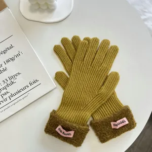 Nahaufnahme von Strickhandschuhen mit Plüschbündchen und rosa Etikett, Texturdetail.