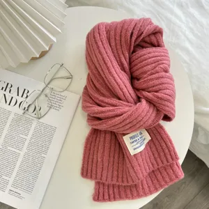 Nahaufnahme eines kuscheligen rosa Rippstrick-Winterschals mit Etikett, eleganter Stil.