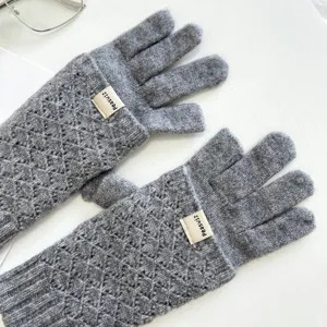 Nahaufnahme Detail grauer Strick Langhandschuhe mit schickem Rauten Zopfmuster und Label.