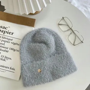 Grey fuzzy knit beanie hat with metallic badge detail, winter warm slouchy wool cap.