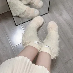 Vue détaillée de jambières duveteuses blanches, guêtres tricotées douillettes pour hiver.