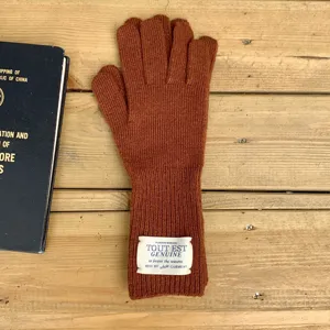 Vue détaillée des gants en laine tricotée marron dotés d'une élégante étiquette blanche au poignet.