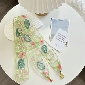Close-up detail of embroidered lace trim with pink floral and green leaves for DIY crafts.