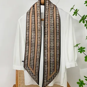 Detailed view of long narrow silk scarf with houndstooth and khaki stripe pattern.