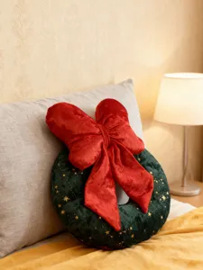 Detailansicht des Weihnachtskranz-Plüschkissens mit roter Schleife und weicher Samtstoff.