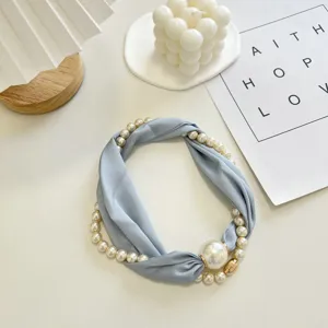 Delicate lichtblauwe stoffen bandketting met kunstparels en een handige magneetsluiting.