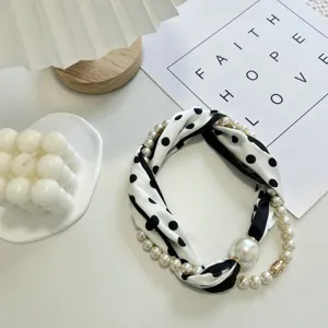 Detail view of the black and white polka dot silk scarf with pearl necklace and magnetic pendant.