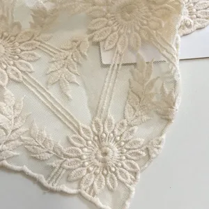 Primo piano di tessuto di pizzo beige con delicati motivi floreali ricamati per copricapo vintage.