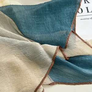 Detailed close-up of pleated contrast edge square scarf, ultra-thin soft sun protection fabric.