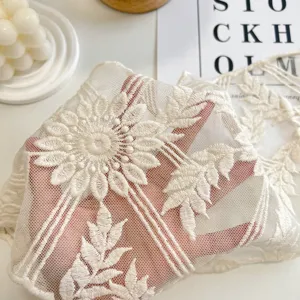 Dettaglio di foulard triangolare in pizzo beige ricamato che mostra la trama della rete.