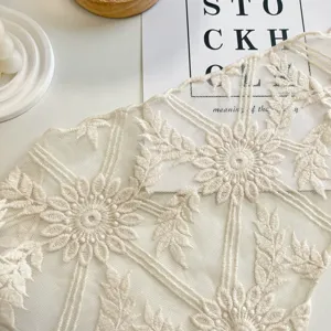 Primo piano dei dettagli della fascia in pizzo beige con ricamo floreale, tessuto a rete.