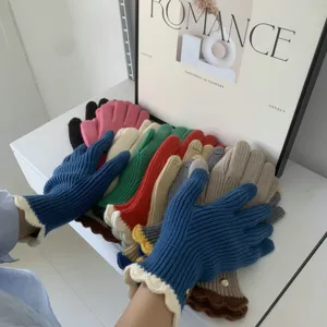 Primo piano dettagliato di caldi guanti in maglia invernali con polsini con volant e colori multipli.