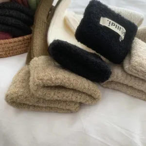 Close-up detail of cozy winter fuzzy knitted gloves and wrist warmers in neutral colors.
