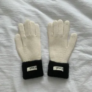 Close-up view of winter knitted gloves featuring black plush cuffs and detailed knit texture.
