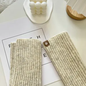 Cozy knitted arm warmers in soft beige, featuring a chic ribbed texture and stylish detail.
