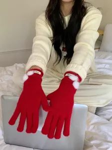 Gedetailleerd overzicht van rood gebreide winterhandschoenen met witte pompons en polsetiket.