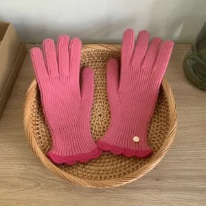 Guanti in maglia rosa dettaglio, con vestibilità elastica a costine e bordo smerlato.