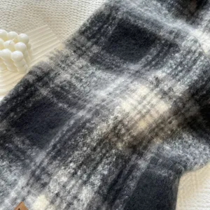 Primer plano detalle de suave bufanda de invierno a cuadros negro y gris textura acogedora.
