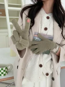 Gedetailleerd overzicht van groene gebreide dameshandschoenen met pluche bal en ontwerp.