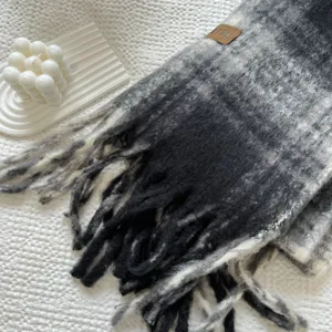 Detalle de bufanda a cuadros gris y negro, textura suave con flecos para el invierno.