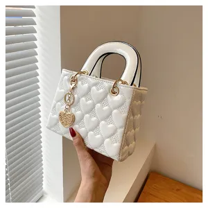 White heart quilted patent leather handbag with top handles and cute heart charm pendant.