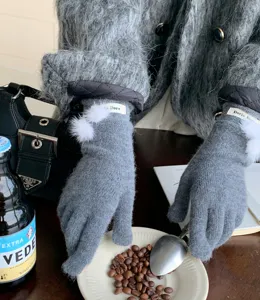 Gedetailleerd overzicht van grijze gebreide wol winterhandschoenen met witte zachte pompons.