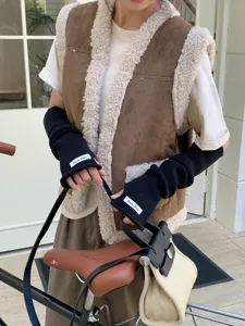 Vue détaillée de longs chauffe-bras tricotés noirs avec petite étiquette de marque pour l'automne.