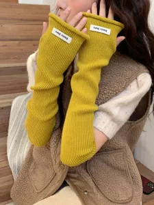 Vue rapprochée des manchons en tricot jaune moutarde, gants sans doigts en détail.