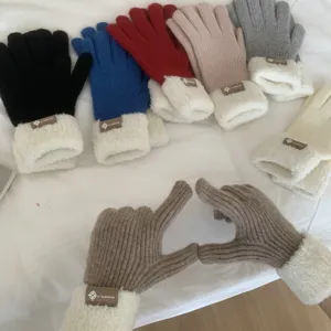 Close-up detail of winter thick warm knitted gloves with fleece cuff and stylish brand tag.