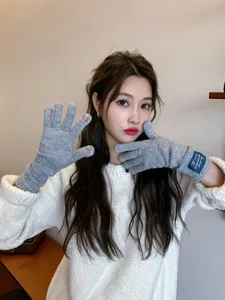 Detailed view of women long knit fingerless gloves in grey with stylish label accent.