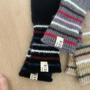 Nahaufnahme von kuscheligen, gestreiften langen Strickhandschuhen für Damen im Winter.