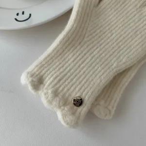 Gros plan de gants tricotés d'hiver pour femmes avec design côtelé et poignets ondulés.