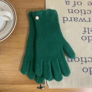 Gros plan des détails de gants tricotés d'hiver, laine vert foncé avec bouton délicat.