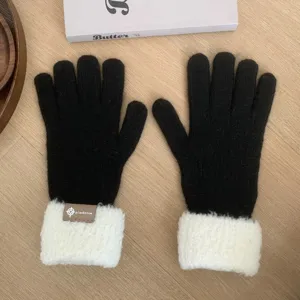 Close-up detail of cozy black knit gloves with warm white plush fleece cuffs for autumn and winter.