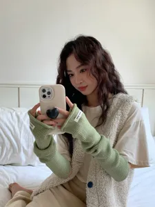 Détail de mitaines en tricot vert, longs gants sans doigts pour femmes, mode hivernale.