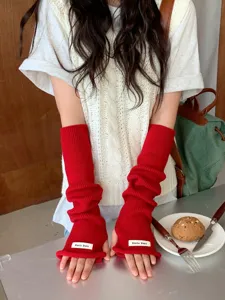 Gros plan détaillé de mitaines en tricot rouge vif, texture confortable, design sans doigts.