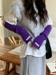 Gros plan de manchons de bras en tricot violet avec étiquette blanche pour femmes.