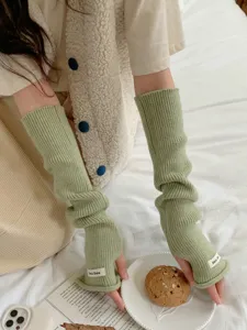 Vue détaillée de longs gants tricotés sans doigts chauffe-bras avec texture côtelée.