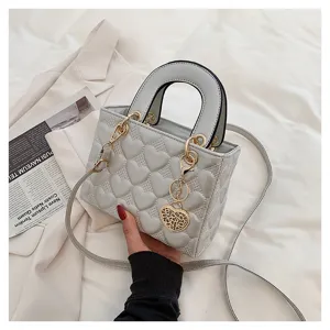 Detailed view of grey heart quilted shoulder handbag with metal heart charm and strap.