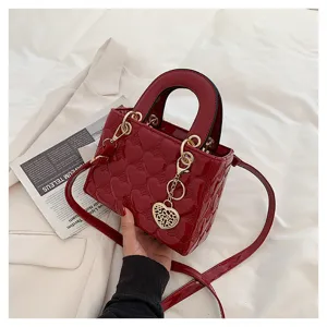 Red patent leather handbag with heart quilting and gold metal chain charm details.