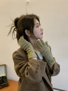 Detailed shot of cute winter knitted long gloves for women, warm five-finger design in solid khaki.
