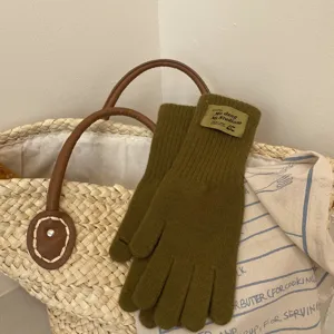Detailed view of cozy olive green knitted winter gloves featuring a stylish woven label.