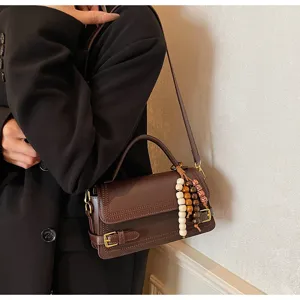Stylish dark brown structured small square shoulder bag with elegant handle and beaded charm detail.