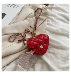 Close-up detail van de rode gewatteerde hartvormige crossbodytas met gouden ketting en bloemsluiting.