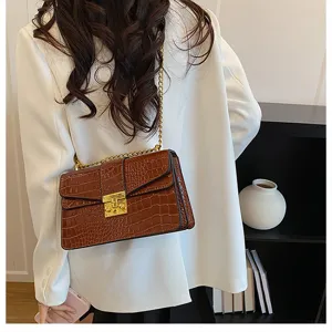 Detailed view of brown crocodile pattern shoulder bag with gold chain strap and metal lock.