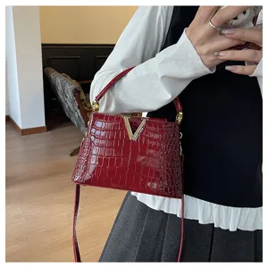 Detail view of the red crocodile embossed shoulder bag with crystal V clasp and chic strap.