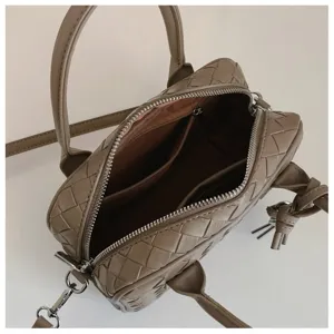 Detailed view of women's woven leather shoulder bag with top handles and chic knot accent.