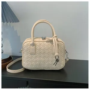 Close-up detail of the beige woven leather handbag, showing exquisite intrecciato craftsmanship.